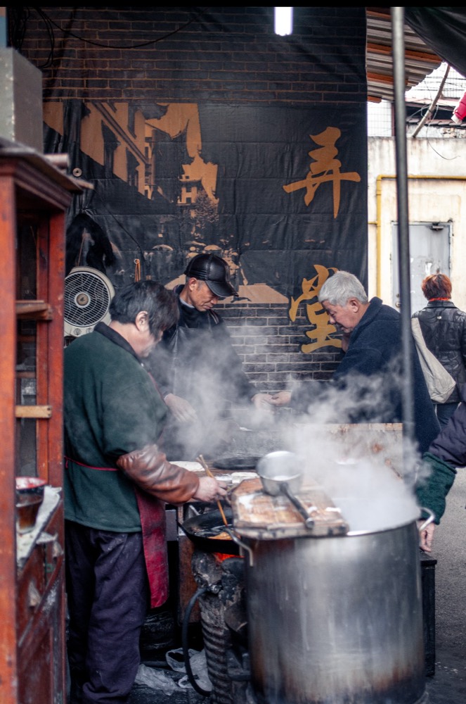 Steam rising from a street-food stall in a Shanghai lane