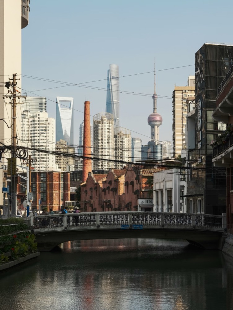 Shanghai skyline seen across a canal and stone bridge
