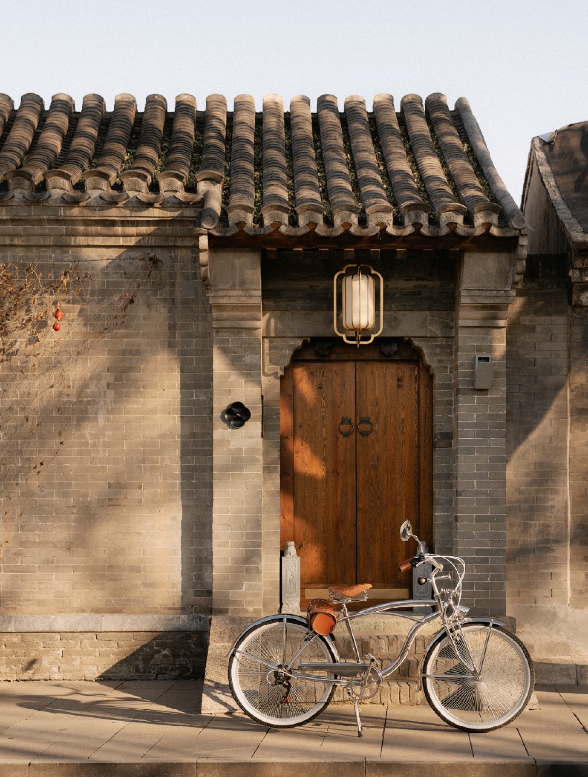 A bicycle against a grey-brick Beijing doorway in warm light