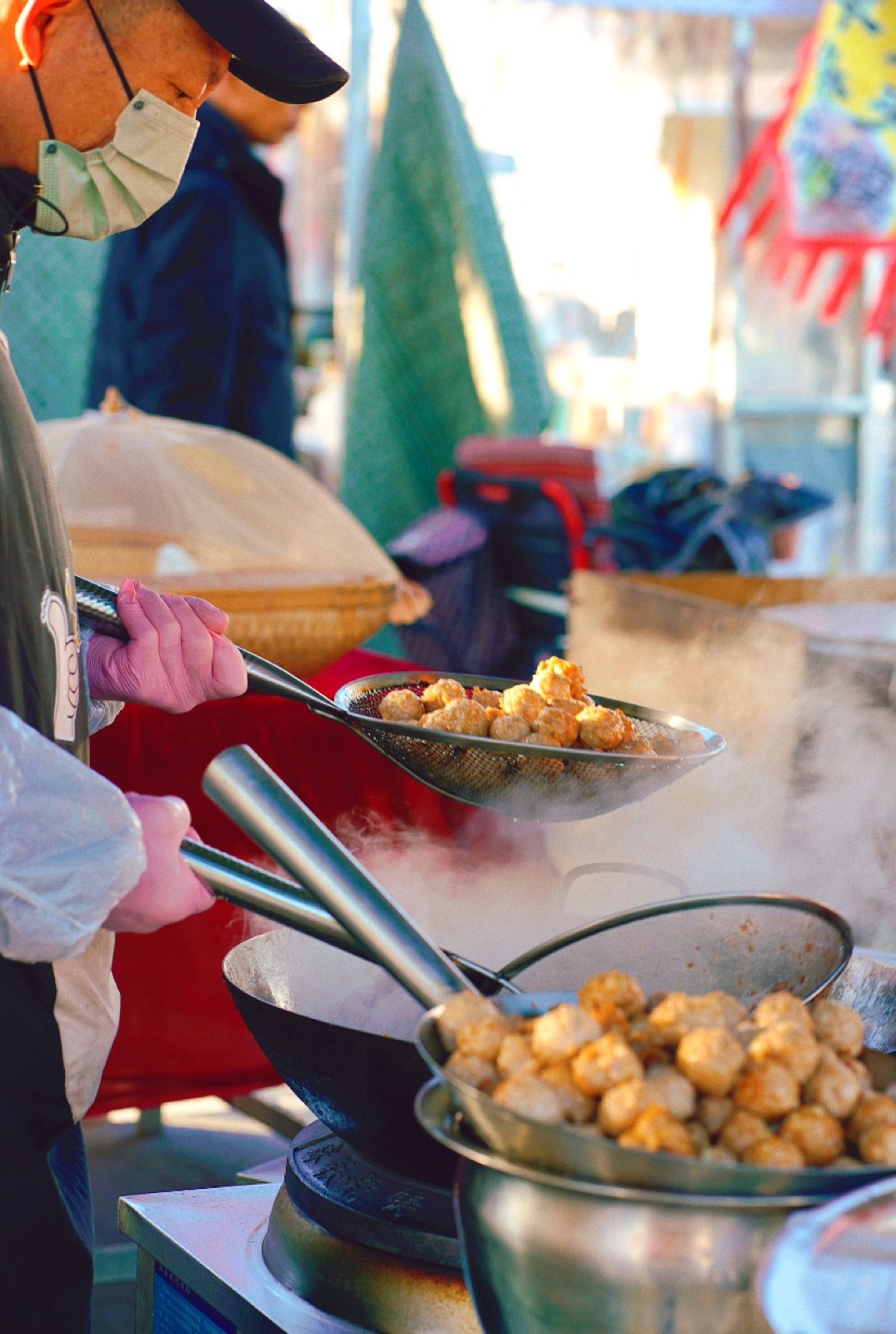 A vendor frying breakfast snacks in steaming woks at a Beijing street stall