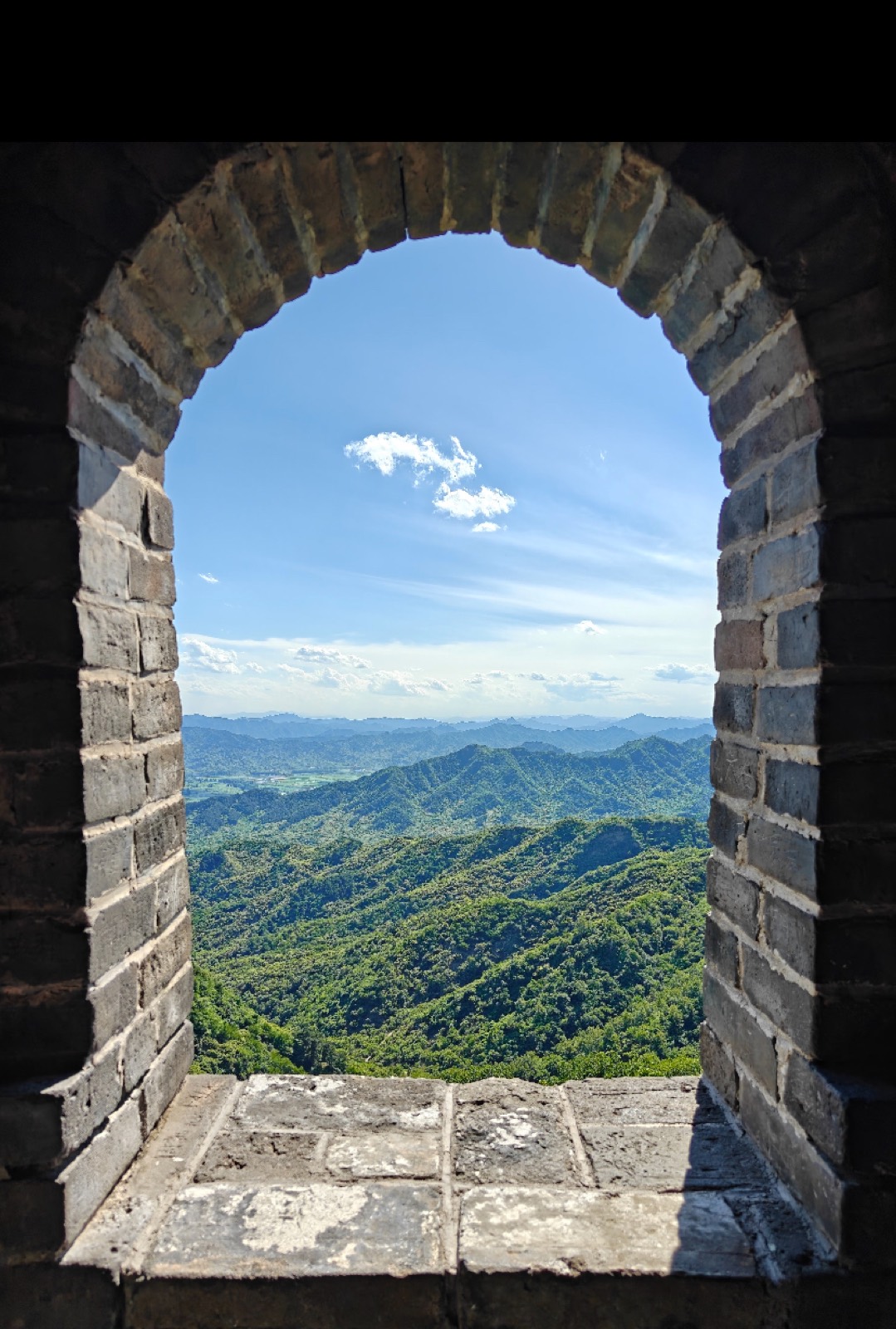 The mountains framed through an arched watchtower window on the Mutianyu Great Wall