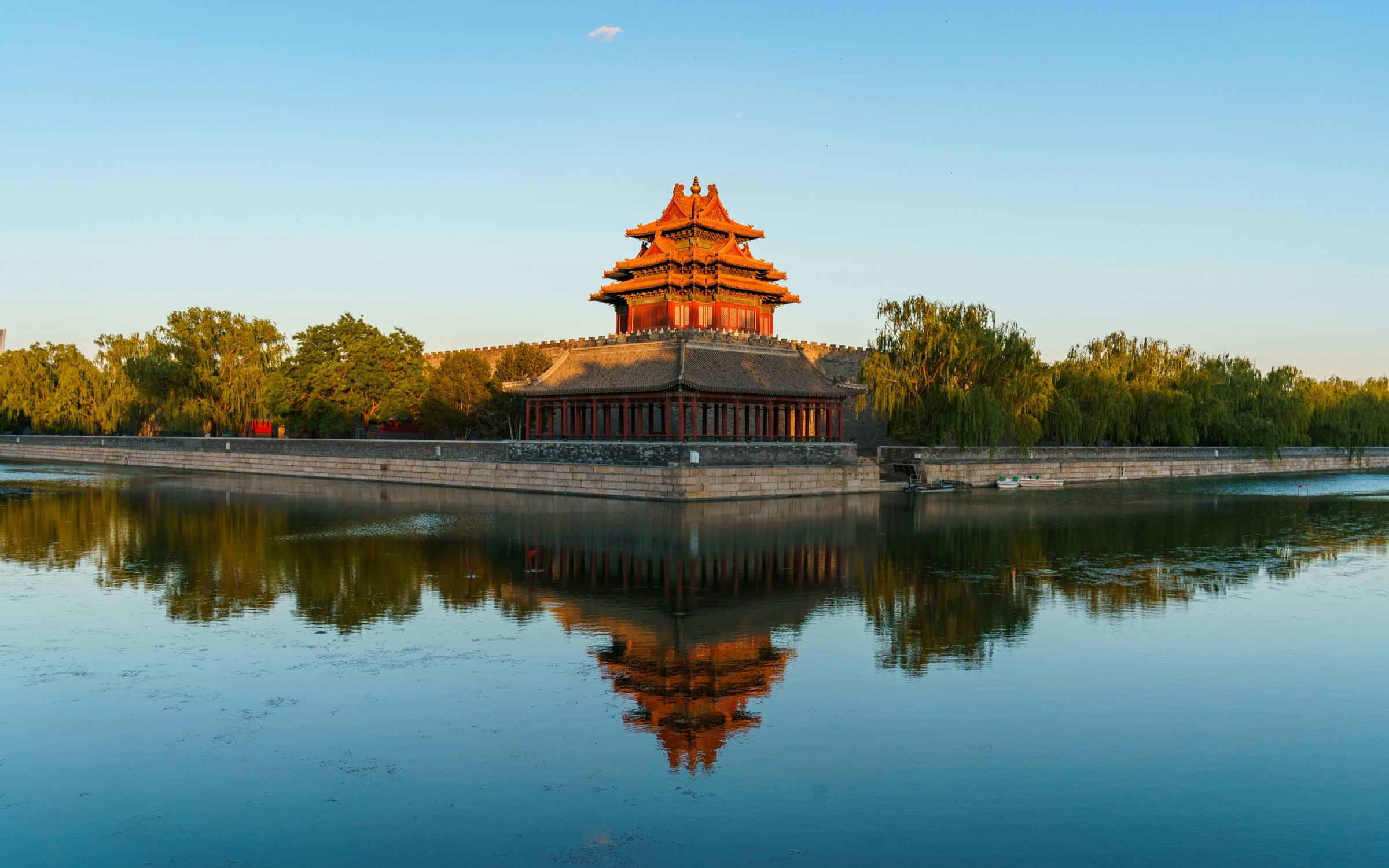 A Forbidden City corner tower mirrored in the moat at golden hour