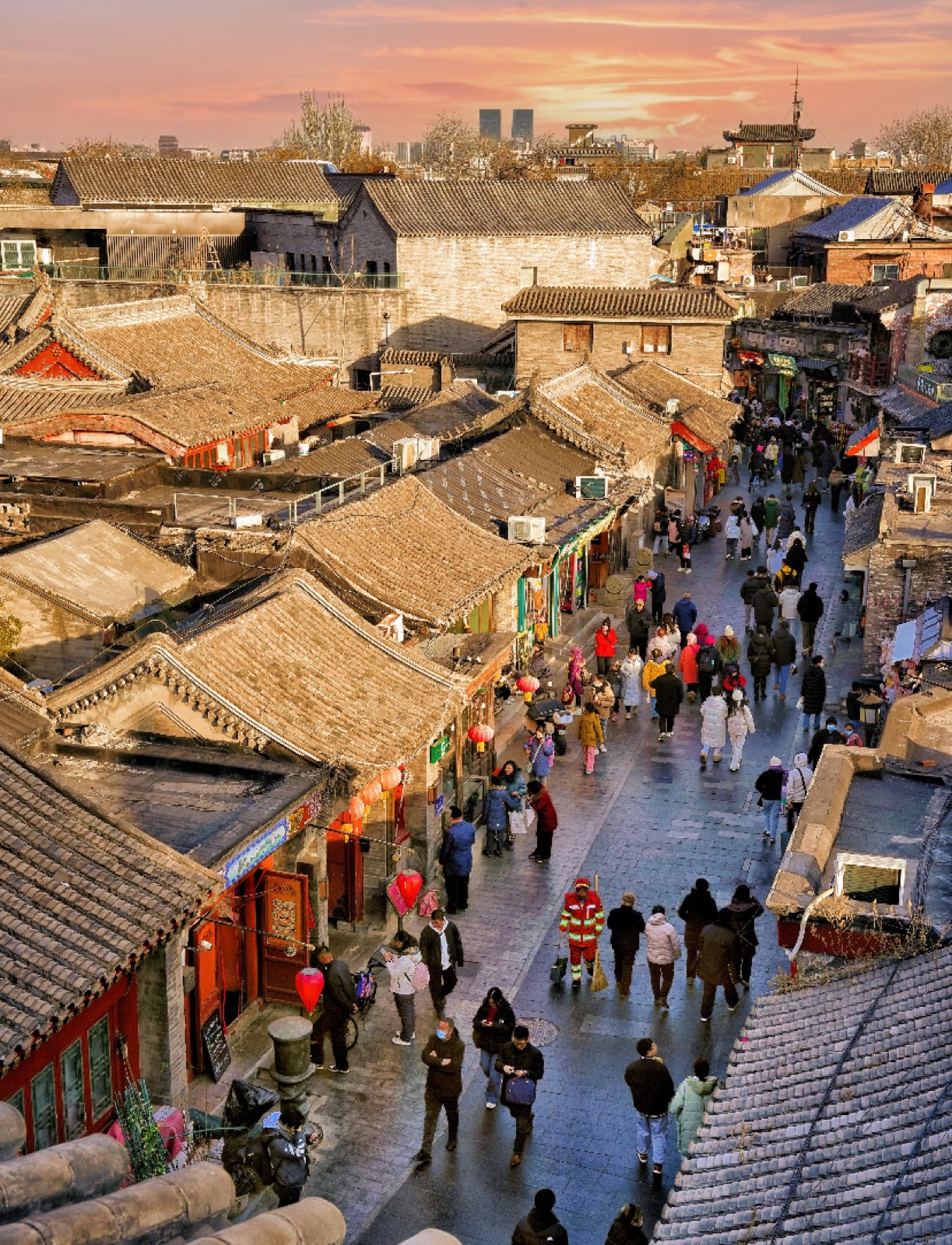 Rooftops and a bustling hutong lane at Nanluoguxiang, Beijing, at sunset