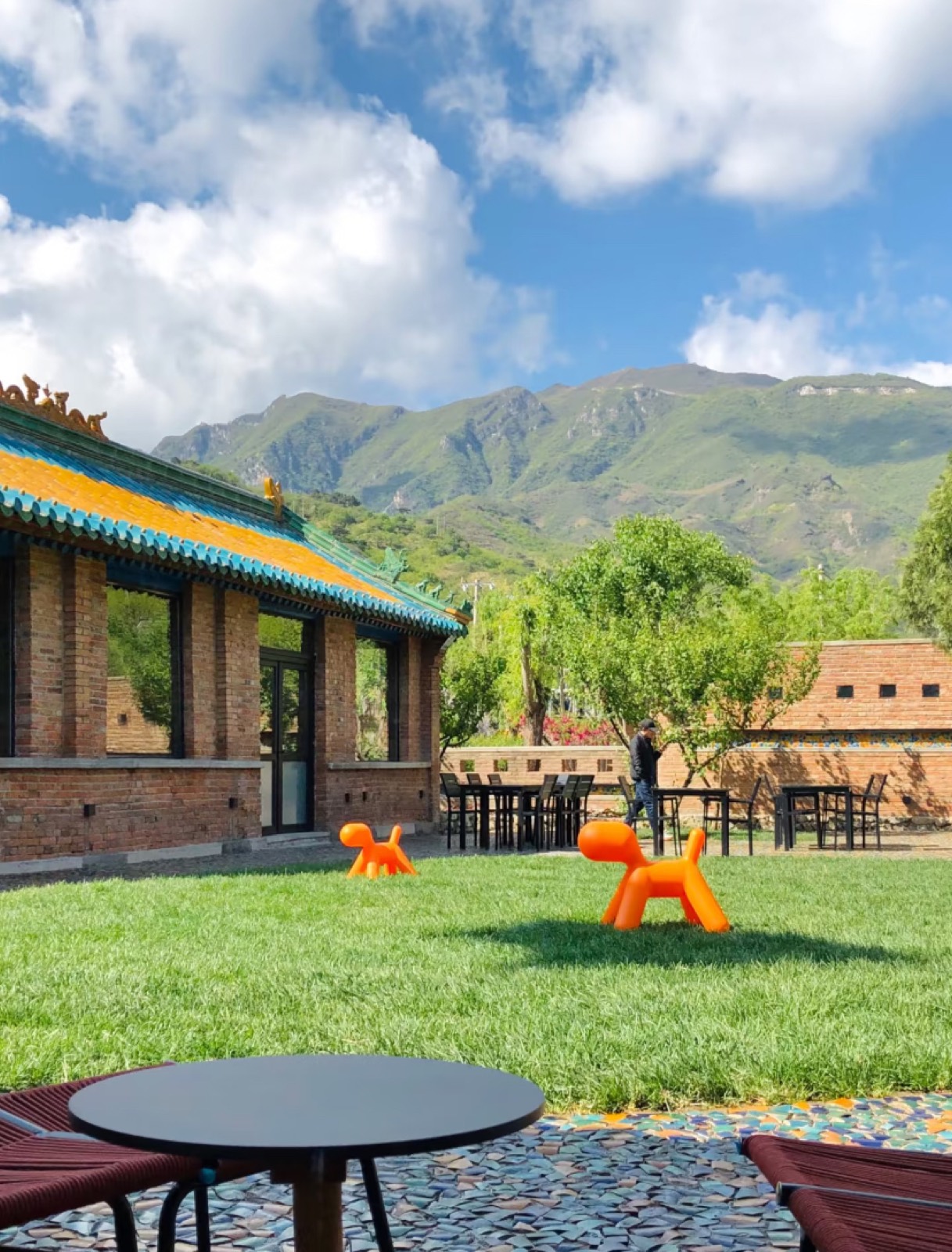 The restored Wachang Village space with a glazed-tile pavilion below green mountains