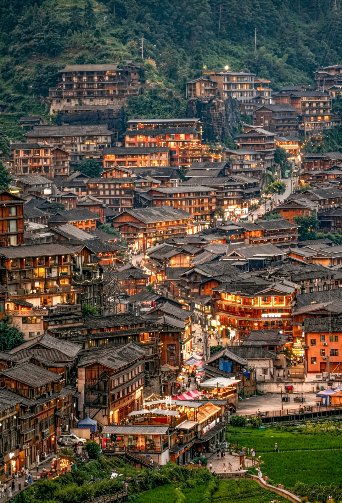 The thousand houses of Xijiang Qianhu Miao Village lit up across the hillside at dusk