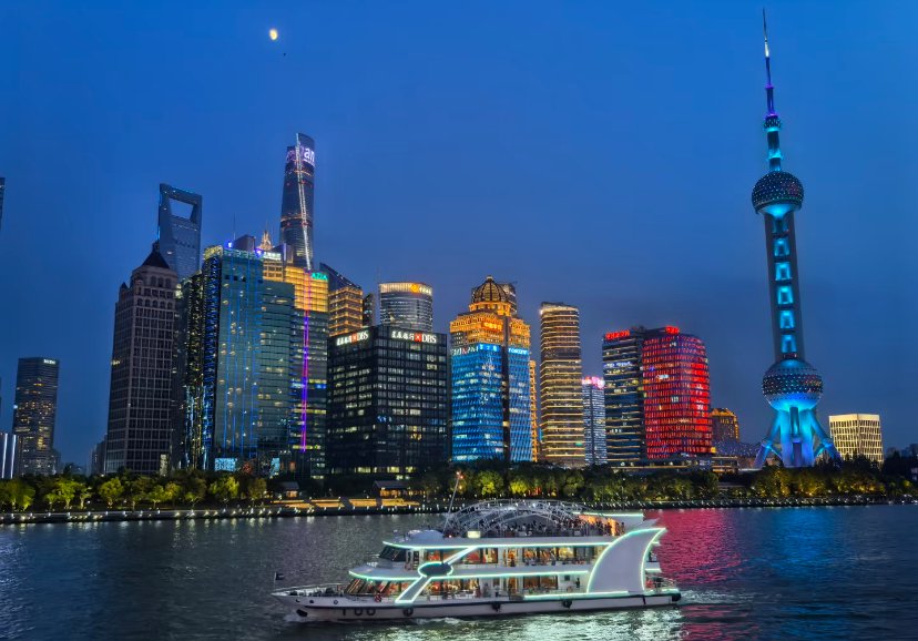 A cruise boat on the Huangpu River with Shanghai's illuminated skyline behind