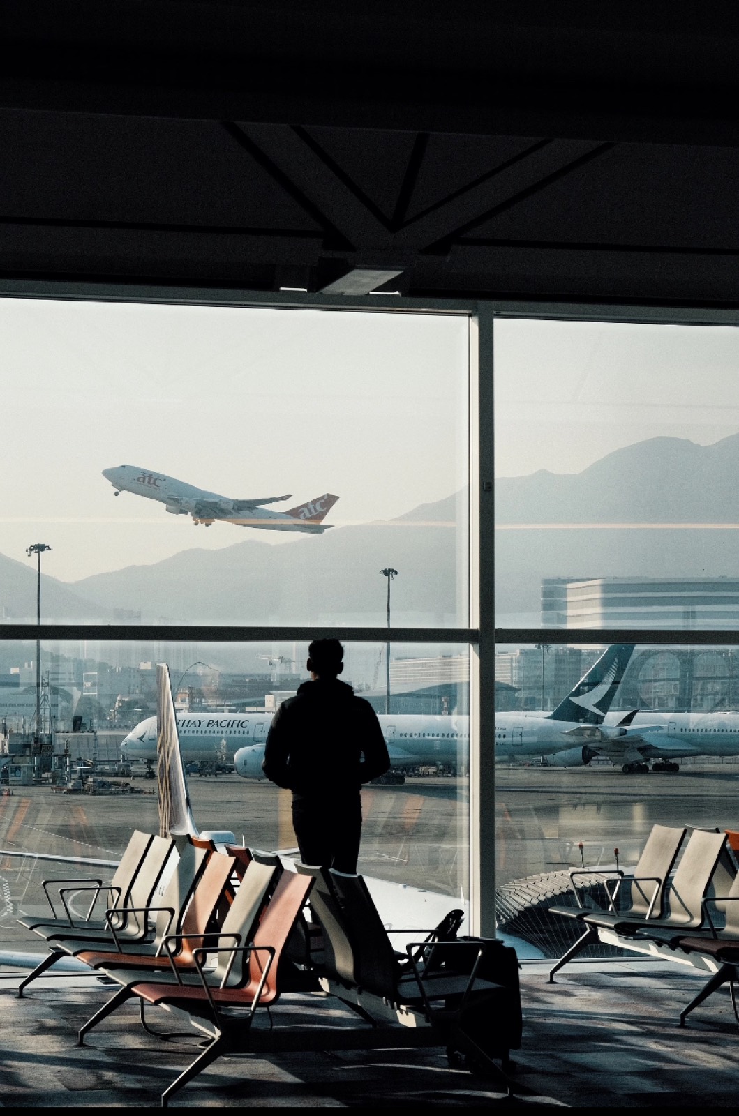 A traveler watching a plane take off from a Shanghai airport terminal