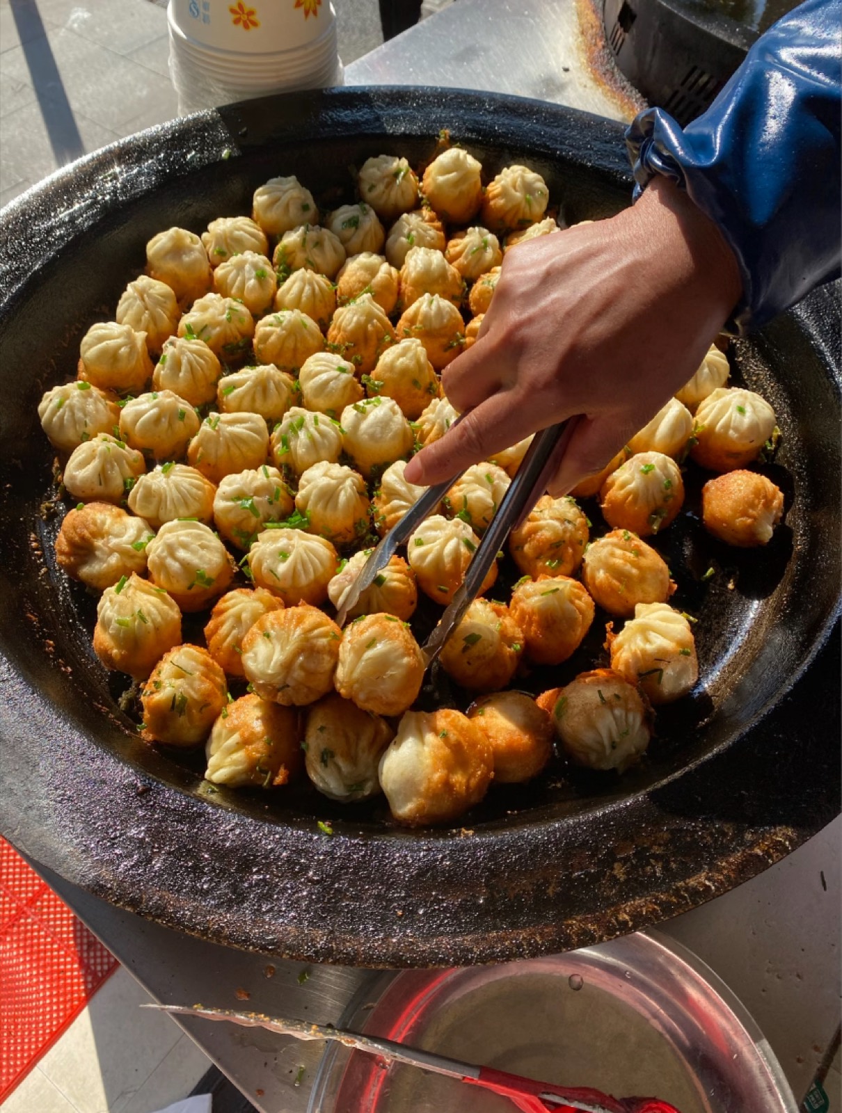 Freshly pan-fried local dumplings sizzling in a wok in Zhujiajiao