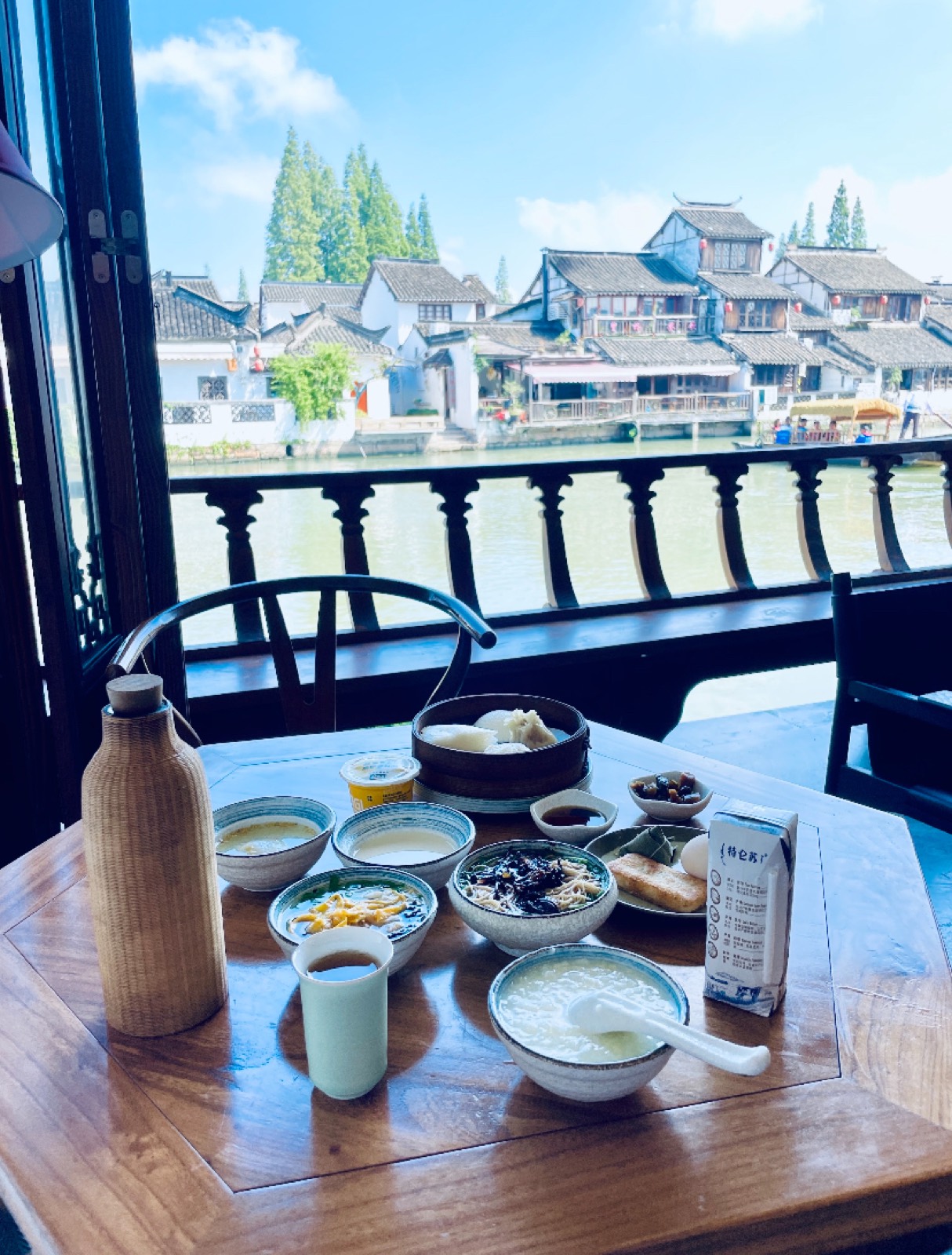 A teahouse table set with tea and snacks overlooking the Zhujiajiao canal
